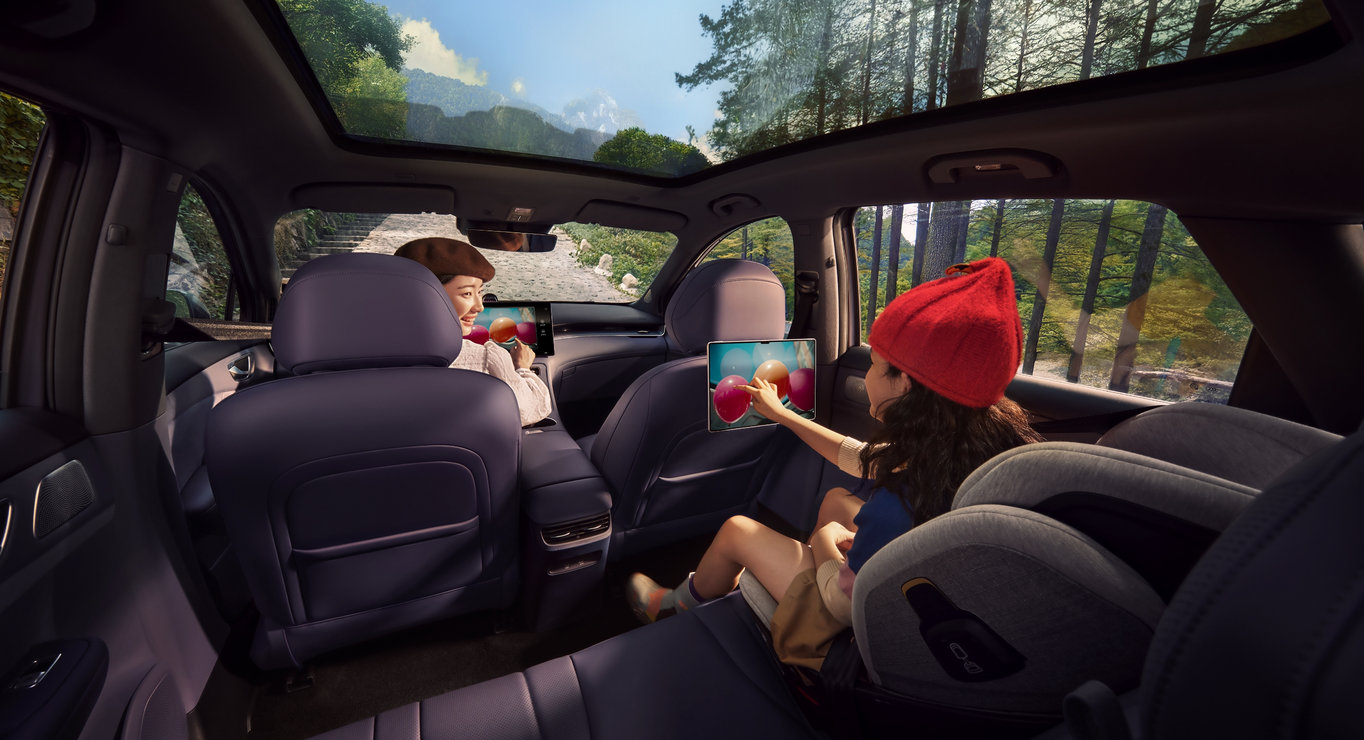 Two individuals seated in the front and rear, sharing the screen simultaneously, demonstrating the Huawei MagLink dual-screen connectivity feature